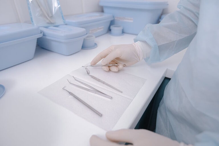 Curetas dentales sobre papel estéril en un entorno clínico, con mano enguantada seleccionando instrumento para tratamiento periodontal.